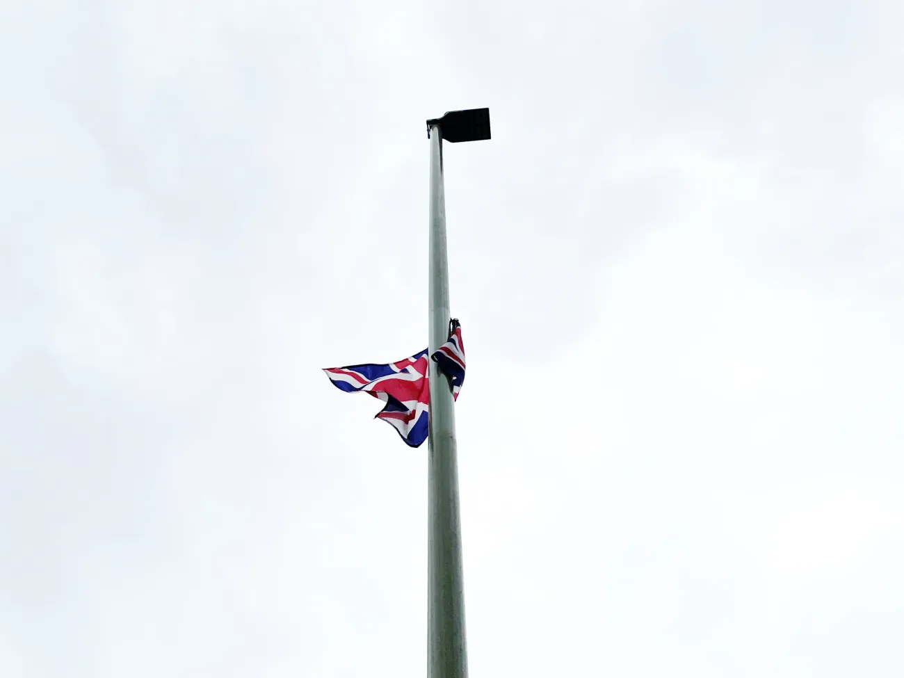 A union jack attached to a lamp post, seen against a grey sky