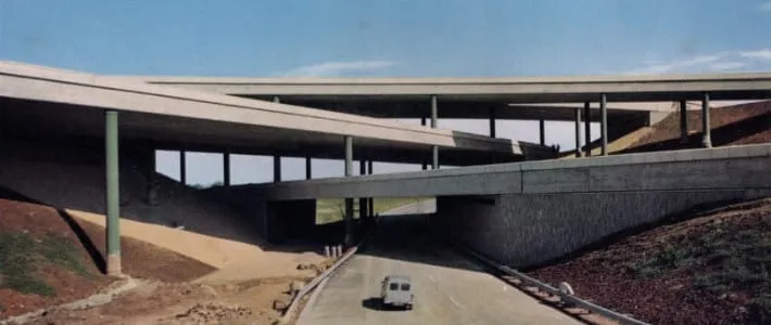 Photograph of four-level motorway junction, with a car passing along a road at the bottom