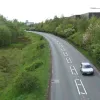 All the junctions are almost precisely a mile apart. Halfway to the first, a footbridge crosses the road between Gorse Covert and the industrial estates to the north. From this bridge we can play our first game of "spot the missing carriageway": most of Birchwood Way was only built as single-carriageway with provision for widening.