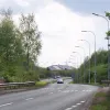 The eastbound approach to the junction. Between here and the next roundabout Birchwood Way is dualled, and there is no shortage of warnings for fast-moving traffic to slow down. The dashed markings nearest the camera are for a bus stop.